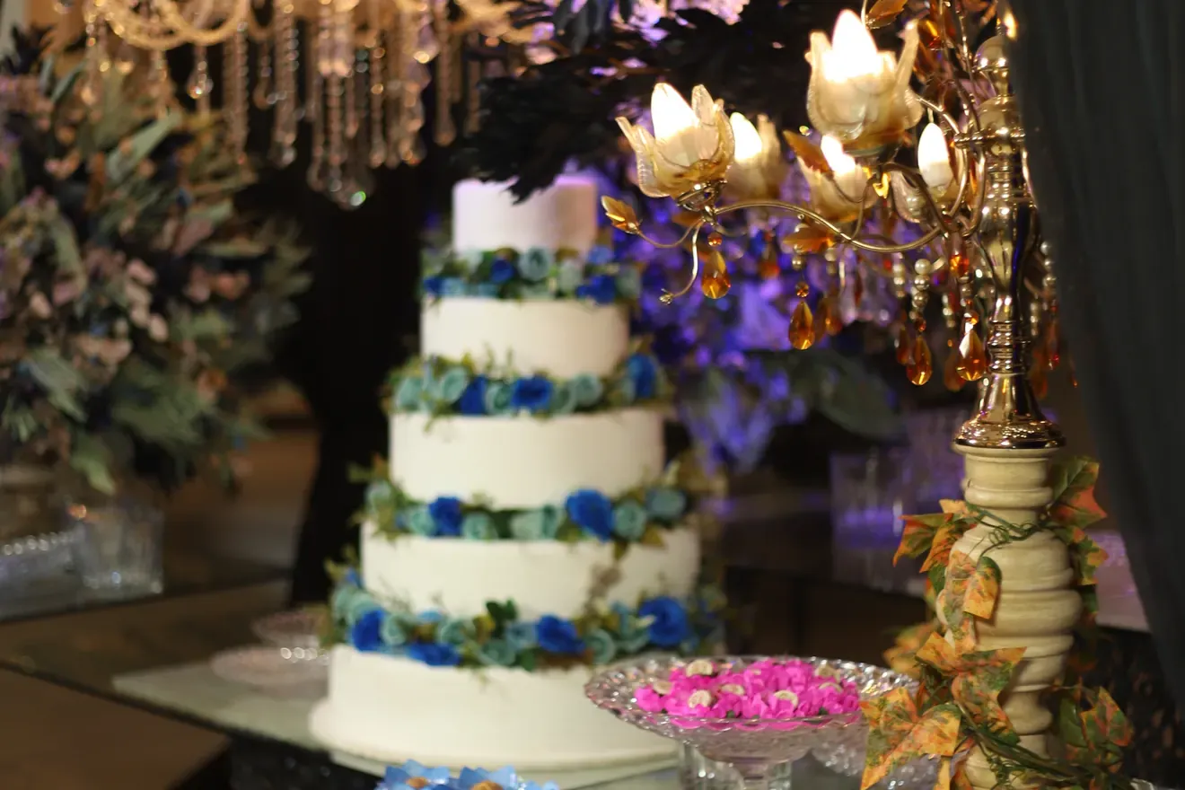 Mesa de doces montada para casamento, com arranjos de forminhas coloridas, bolo e candelabros